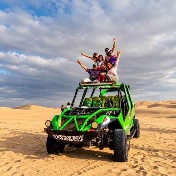 A green off-road vehicle with passengers enjoying a desert landscape. 3