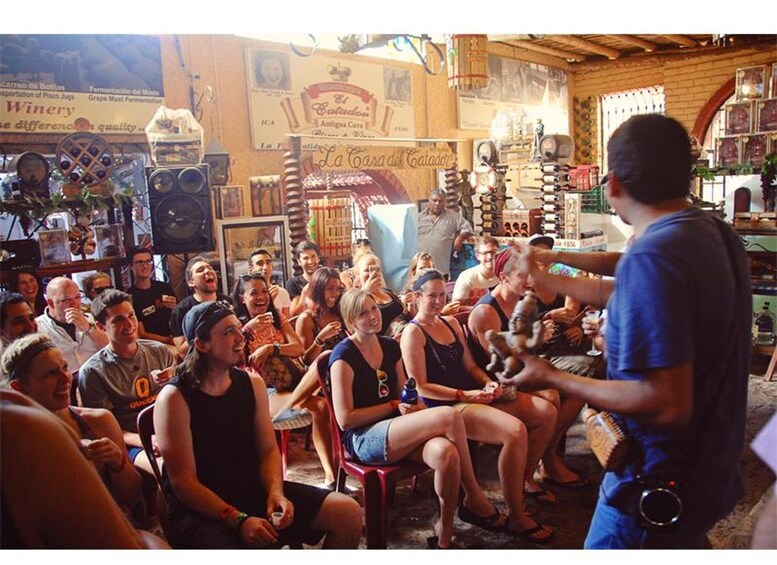A group of people seated in a rustic indoor setting with wooden walls and various signs, including one that reads 'La Casa del Catador.' 4