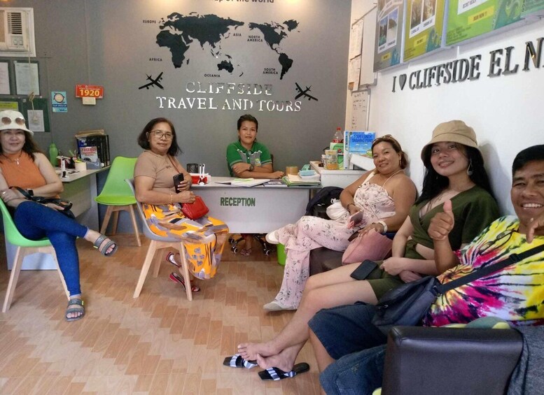 A travel agency reception area with a world map and 'Cliffside El Nido Travel and Tours' sign. 1