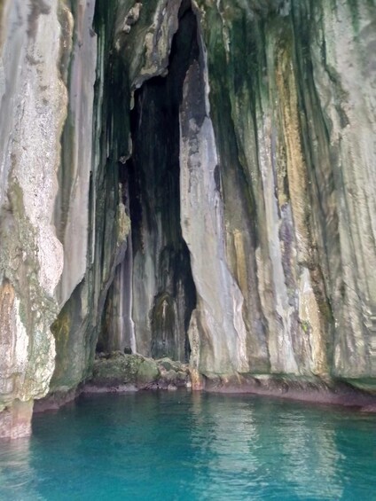 A cave with turquoise water at the bottom. 5