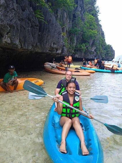 A group of people in kayaks and rafts at a rocky coastal area. 4