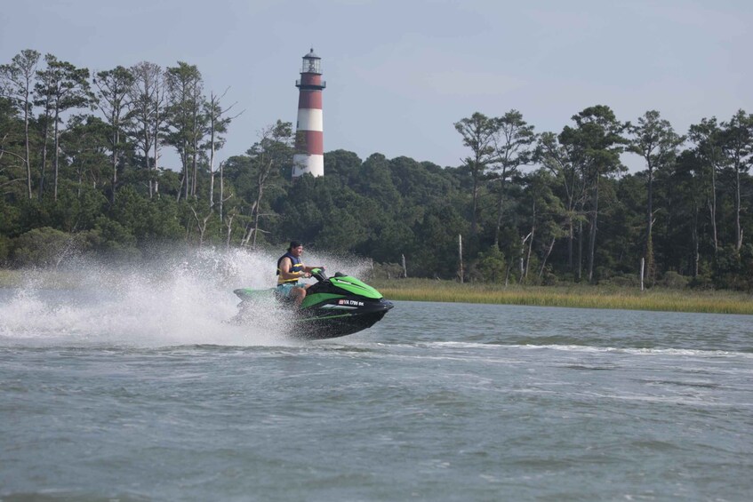 A person jet-skiing on a lake with a lighthouse in the background. 4