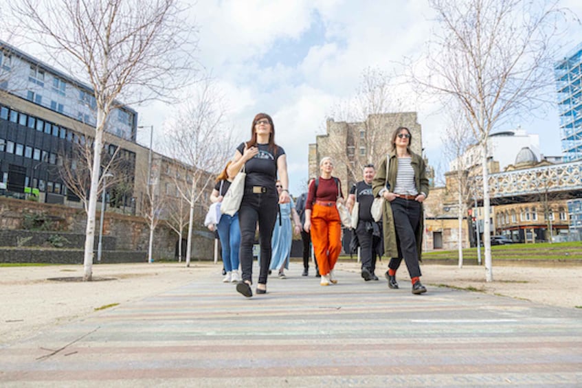 A group of people walking on a pedestrian path in an urban area with modern buildings and trees. 1