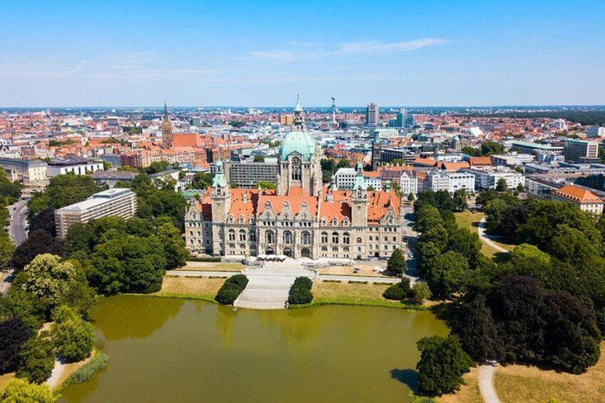 A historic building with a green dome, surrounded by a moat and trees, in a cityscape. 4