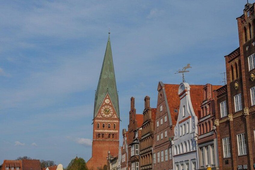A historic church with a tall spire, adjacent traditional buildings, and a clear sky. 3
