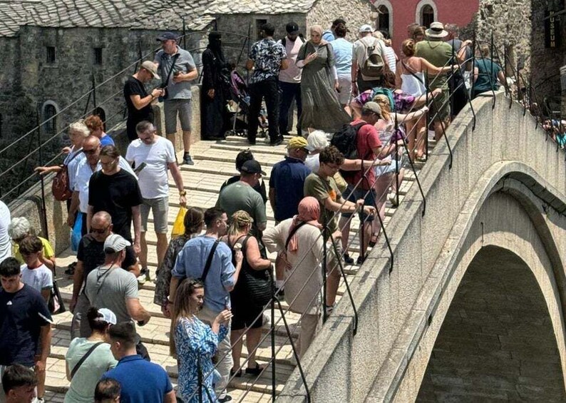 A crowded stone bridge with people walking and standing. 5