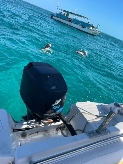 A boat with a visible outboard motor labeled 'M 150' and a person swimming in the water. 2