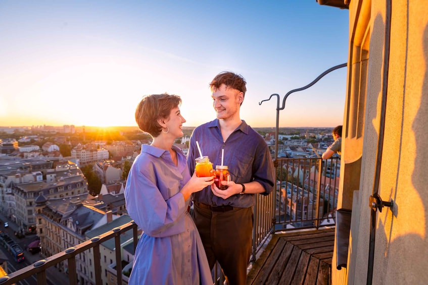 A couple on a balcony overlooking a cityscape during sunset. 1