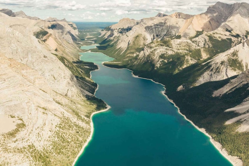 A turquoise lake surrounded by rugged mountains and sparse vegetation. 3