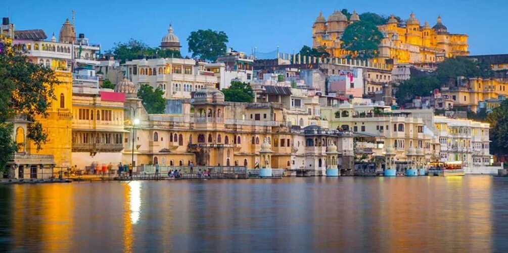 A historic cityscape with a river in the foreground and a hilltop palace in the background. 1