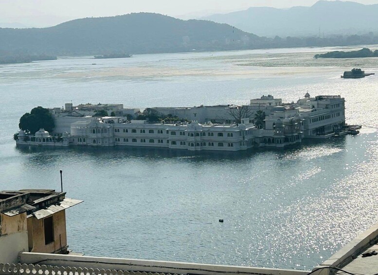 A large, multi-story building with a white facade, situated on a river island. 5