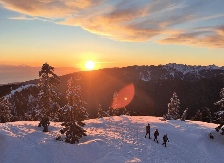 A snowy mountain landscape at sunset with a sun setting behind the peaks. 2