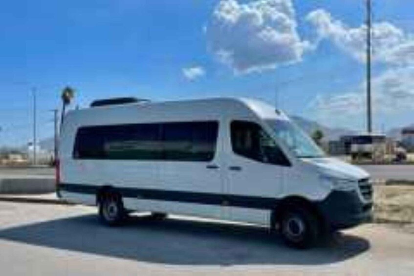 A white van parked on a road with a clear blue sky and some clouds in the background. 1