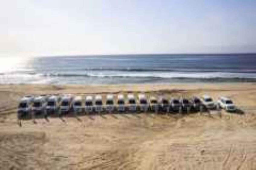 A row of vehicles parked on a beach. 2