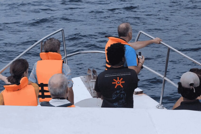 People on a boat wearing life jackets, with one person taking a photo. 2