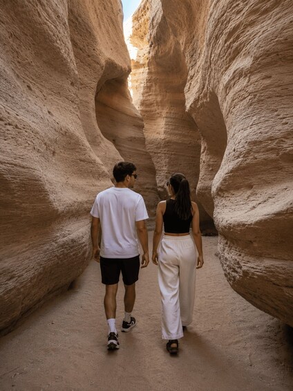 A couple walking through a narrow canyon with towering rock walls. 4
