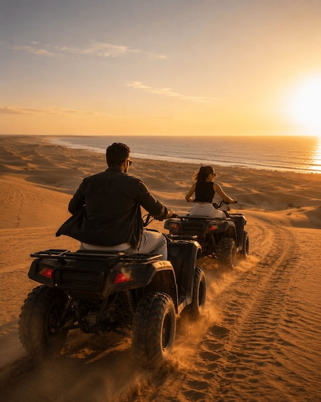 Two people riding ATVs on a sandy beach with the ocean in the background. 1