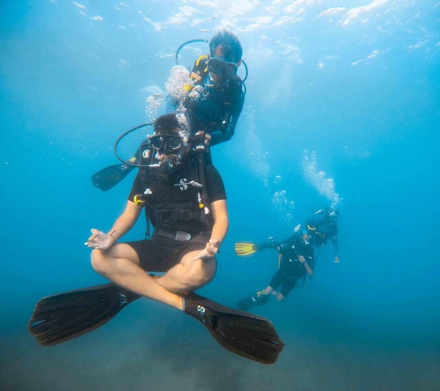 Two scuba divers underwater with fins and tanks. 1