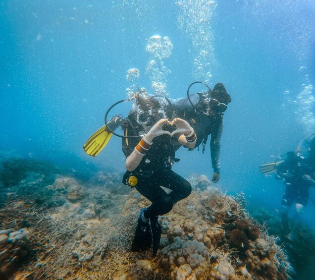 Two scuba divers underwater with coral formations and bubbles. 4