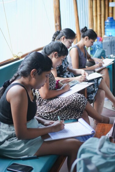 Students seated at desks, engaged in writing or reading. 2