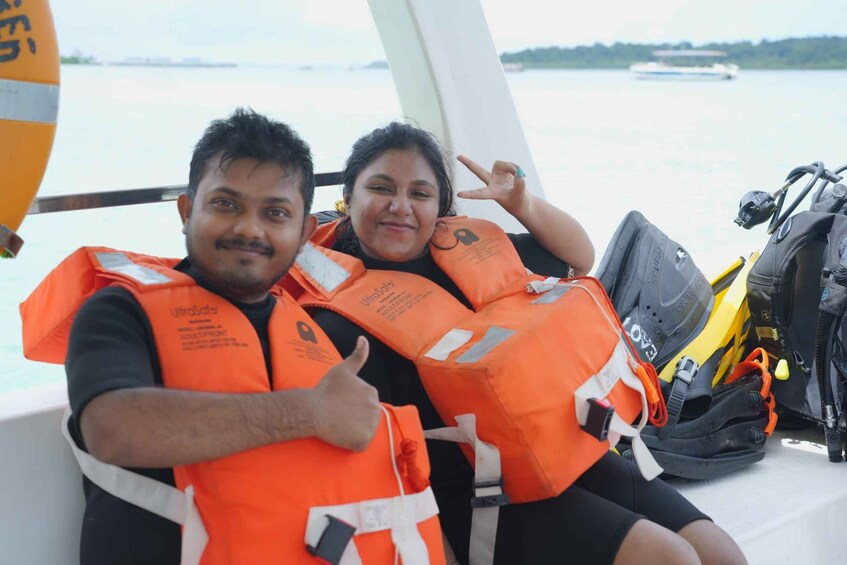Two people wearing life jackets on a boat with a water body in the background. 3