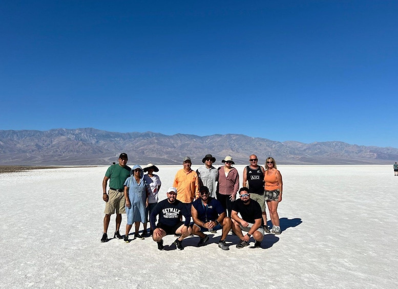 Un groupe de personnes posant dans une étendue de sel, avec des montagnes en arrière-plan. 2