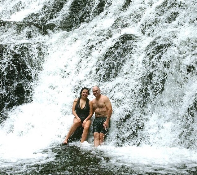 Ein Paar sitzt auf einem Felsen an einem Wasserfall. 2