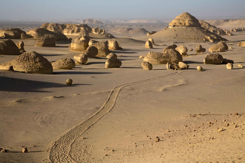A desert landscape with large rock formations and a winding path. 5