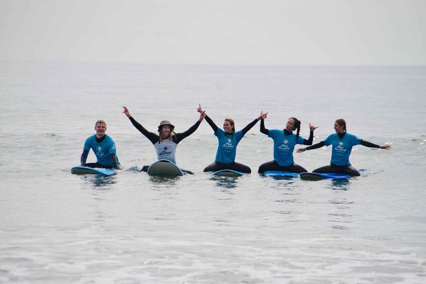 Five people on surfboards in the ocean. 1