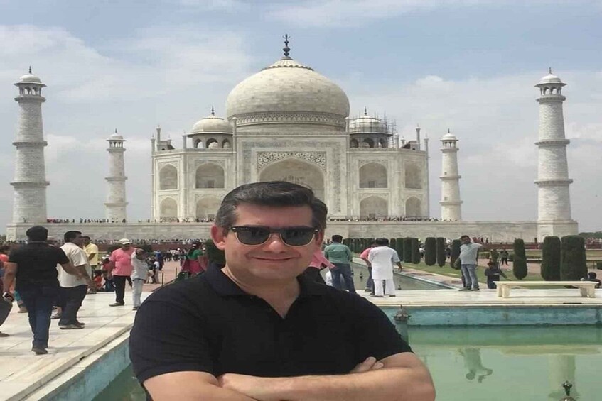 Mies seisoo Taj Mahalin edessä, taustalla näkyvät sen neljä minareettia ja keskusdome. 2