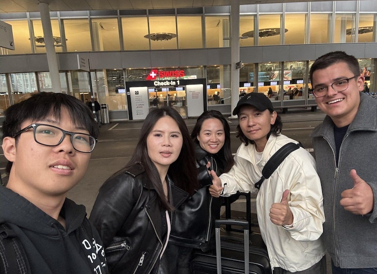 A group of people at an airport with a Swiss Check-In 1 sign. 1