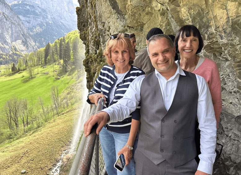 A group of people standing by a rocky cliff overlooking a green valley. 4