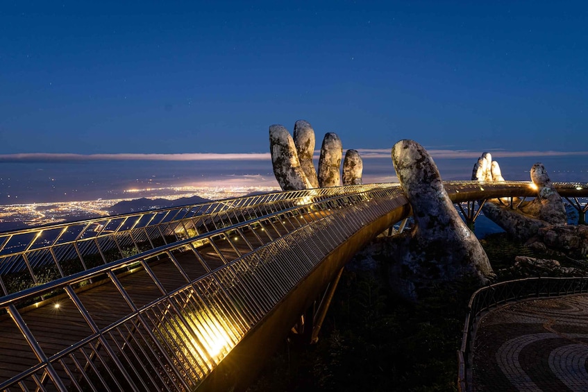 A nighttime view of a bridge with illuminated railings, surrounded by large rock formations. 1