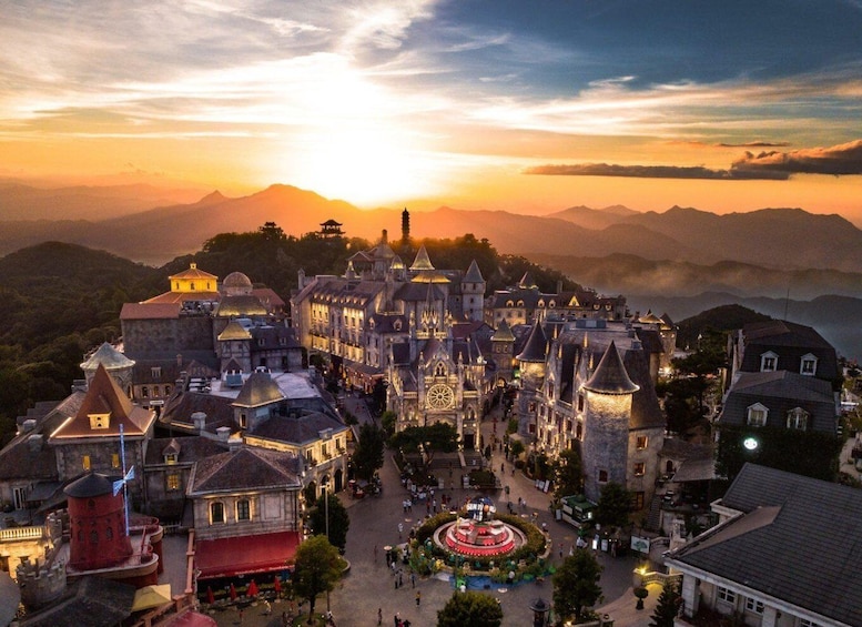 A castle-like structure with multiple towers and a central courtyard, surrounded by mountains and set against a sunset sky. 2