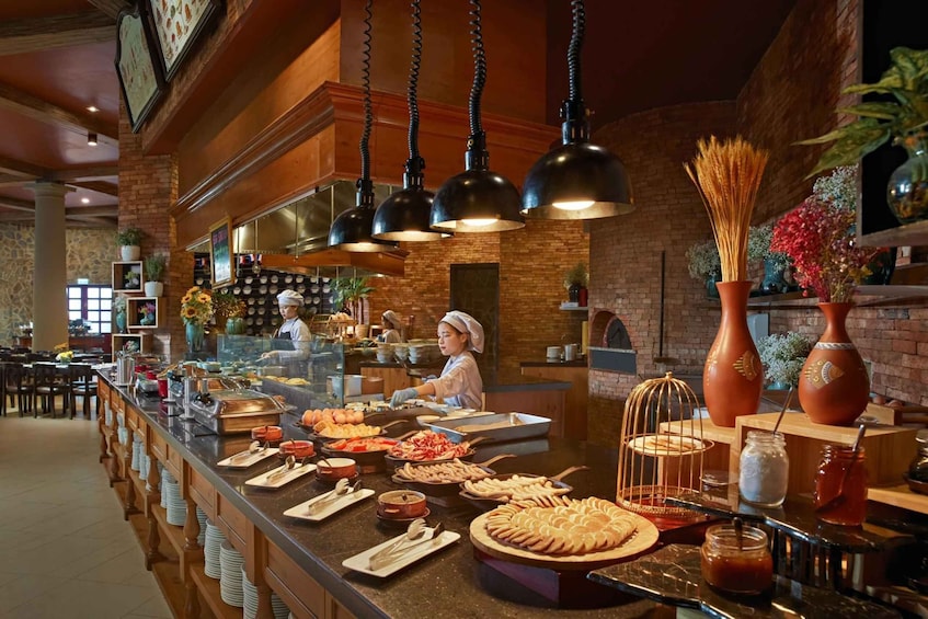 A buffet with various food items, a chef preparing food, and a rustic interior with brick walls and hanging lights. 4
