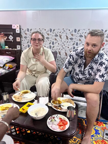 Two people sitting at a table with various dishes, including rice, vegetables, and curry. 1