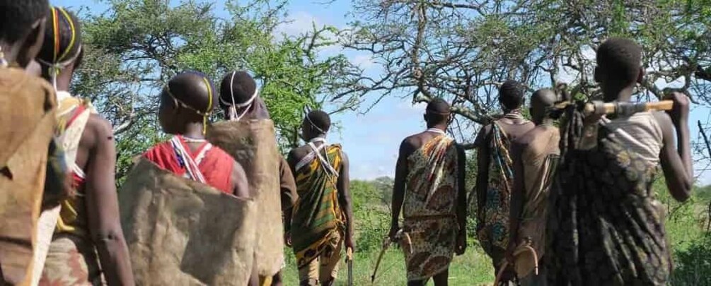 A group of people in traditional attire walking through a natural landscape. 3