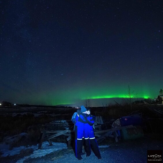 Two people standing under a starry sky with the aurora borealis. 2