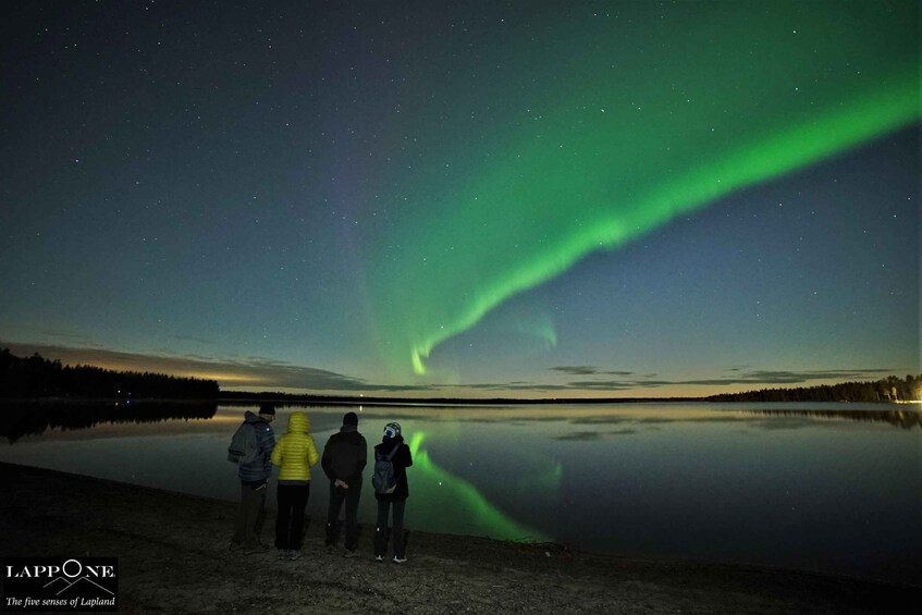 People standing by a lake watching the Northern Lights. 5