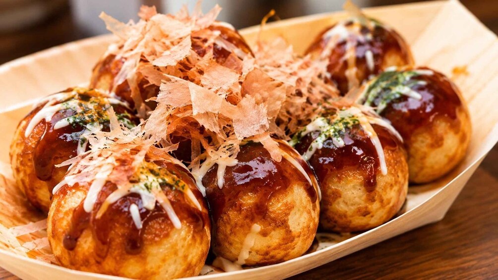 A tray of Japanese takoyaki balls topped with bonito flakes and mayonnaise. 4