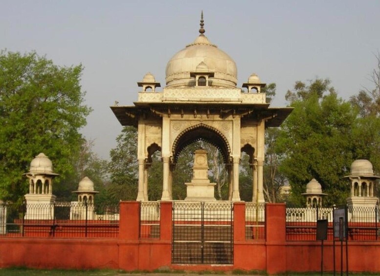 A historical monument with a central dome, surrounded by a red wall and a metal fence. 4