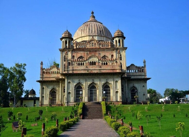 A large, ornate building with a central dome and smaller domes on either side, surrounded by a well-maintained garden. 1