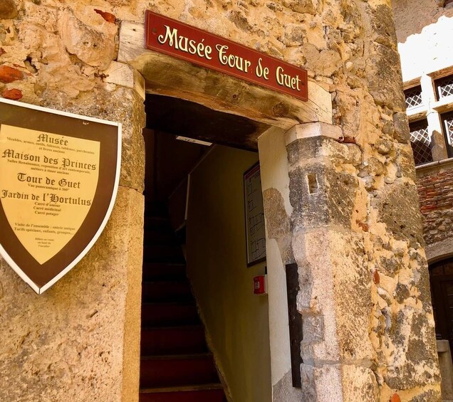 A stone building entrance with a sign reading "Musee Tour de Guet". 3