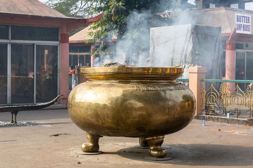 A brass stove emitting smoke, with a sign reading 'Butter Lamp House' in the background. 3