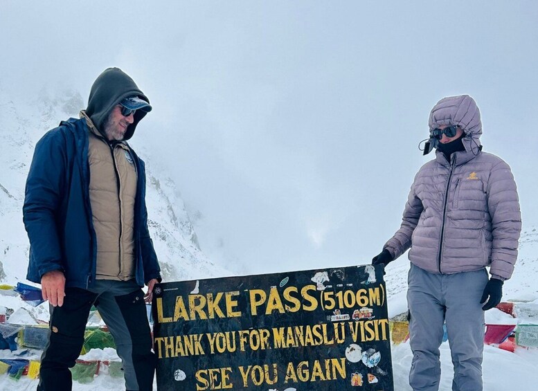 Two people holding a sign at the base of a mountain. 5