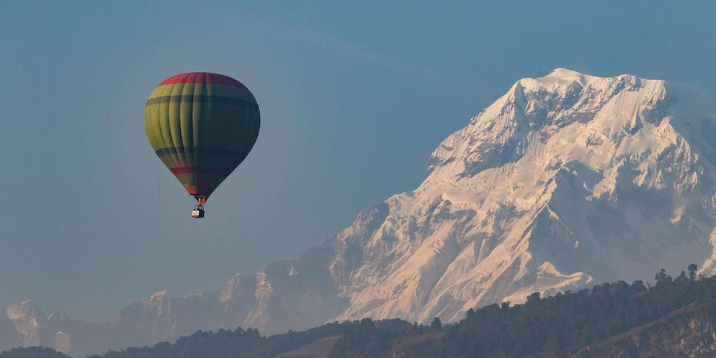 A hot air balloon flying over a snow-capped mountain. 3