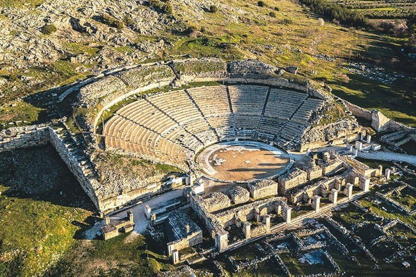 An ancient amphitheater with a circular stage and tiered seating. 1