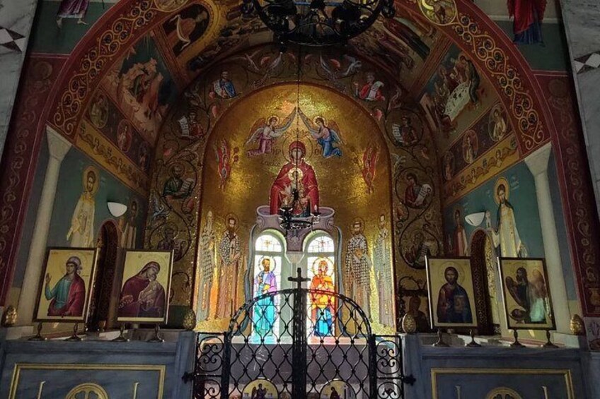 A religious interior with a central iconostasis, religious paintings, and a golden dome. 5