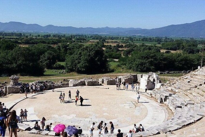An ancient amphitheater with ruins and people. 2