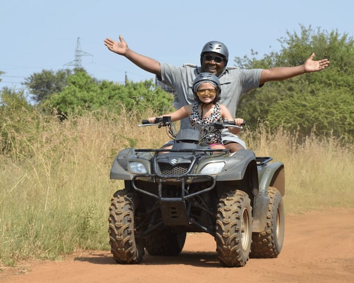 A person riding an ATV on a dirt road with trees in the background. 2